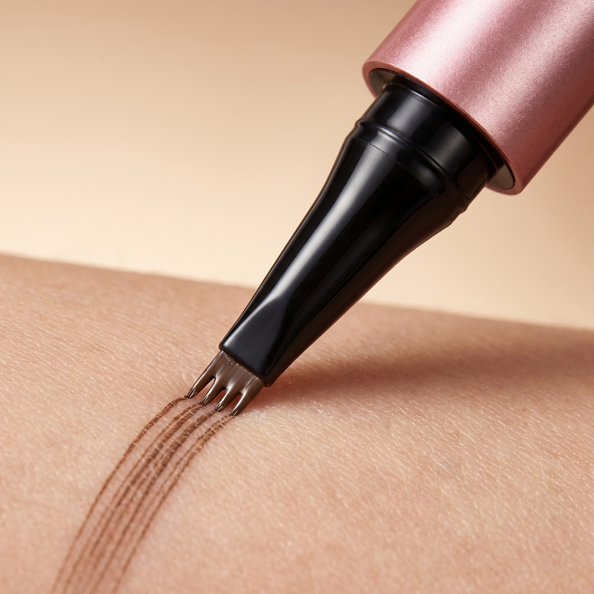 Macro close-up of the four-prong nib drawing four fine hair-like strokes on skin